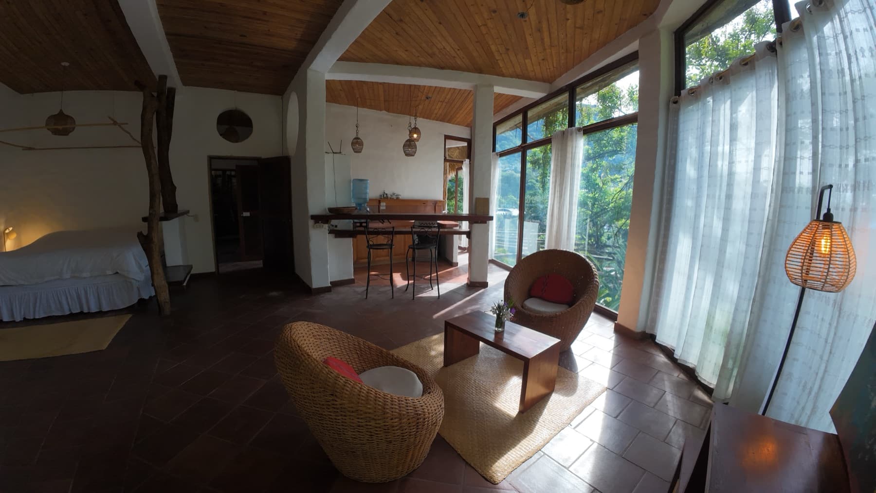 Living room with a kitchenette bar, wicker chairs and garden view